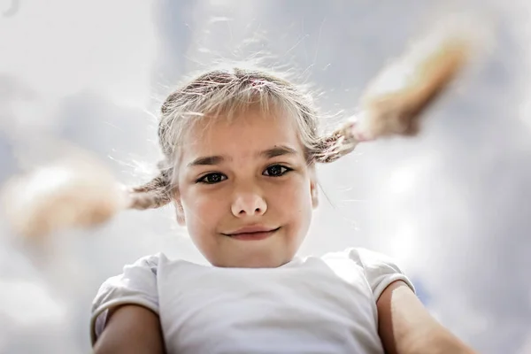 Close-up candid portrait of cute girl with two funny braids taken up at the sky from the ground — Stock Photo, Image