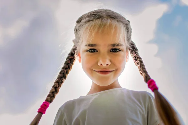 Close-up szczery portret cute girl z dwóch zabawnych warkoczach podjęte na niebie z ziemi — Zdjęcie stockowe