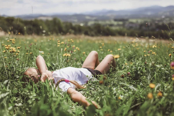 Vonzó lány pihenés a zöld füvön a hegytetőn reggel — Stock Fotó