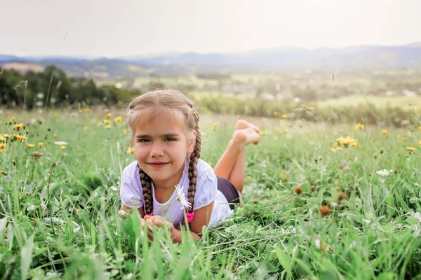 Aantrekkelijk meisje ontspannen op het groene gras op de top van de bergen in de ochtend — Stockfoto