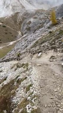Dolomitlerdeki kayalık dağ yolunda yürüyen yürüyüş direkleri olan kadın yürüyüşçü. Yüksek kaliteli FullHD görüntüler