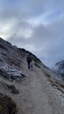 Dolomitler İtalya 'sında köpekli bir adam sisli dağ yolunda yürüyüş yapıyor. Yüksek kaliteli FullHD görüntüler