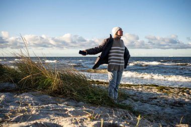 Baltık deniz kıyısında rüzgarlı kış gününün tadını çıkaran bir kadın. Yüksek kalite fotoğraf