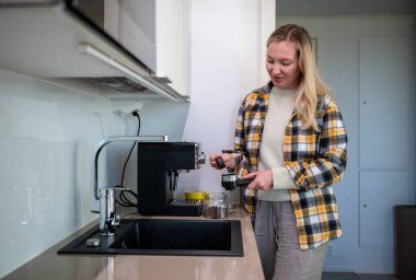 Kadın modern mutfakta ev yapımı espresso makinesiyle kahve hazırlıyor. Yüksek kalite fotoğraf