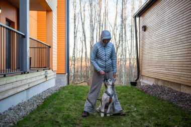 Soğuk bir sonbahar gününde kadın köpek eğitirken avluya çıkmış. Yüksek kalite fotoğraf