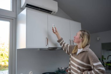 Kadın evdeki klimayı uzaktan kumandayla ayarlıyor. Yüksek kalite fotoğraf