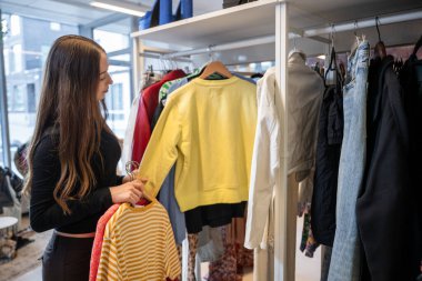 Young woman selecting clothes in secondhand store. High quality photo