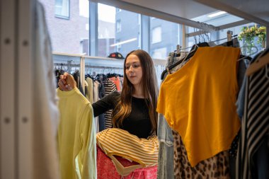 İkinci el mağazasında kıyafet seçen genç bir kadın. Yüksek kalite fotoğraf