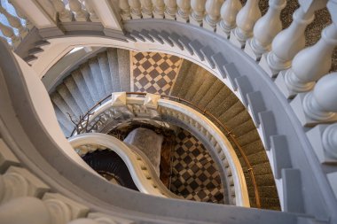 Geometrik fayanslı zemini ve klasik balüstratı olan zarif spiral merdiven. Yüksek kalite fotoğraf