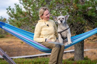 Hamakta rahatlayan bir kadın ve orman doğasında açık havada giyinen bir köpek. Yüksek kalite fotoğraf