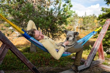 Hamakta rahatlayan bir kadın ve orman doğasında açık havada giyinen bir köpek. Yüksek kalite fotoğraf
