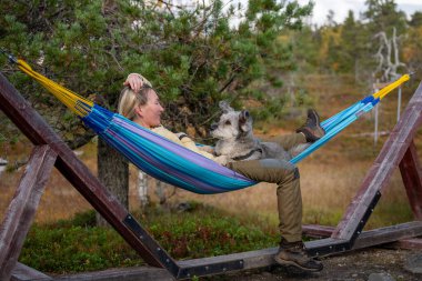 Hamakta rahatlayan bir kadın ve orman doğasında açık havada giyinen bir köpek. Yüksek kalite fotoğraf