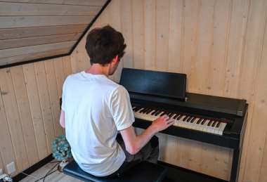 Man playing piano keyboard in cozy home interior. High quality photo