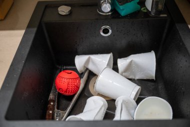 Günlük ev temizliği sırasında lavaboda kirli plastik bardaklar ve mutfak aletleri. Yüksek kalite fotoğraf