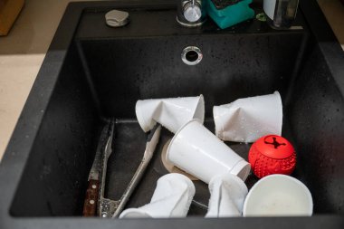 Günlük ev temizliği sırasında lavaboda kirli plastik bardaklar ve mutfak aletleri. Yüksek kalite fotoğraf