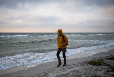 Yalnız adam bulutlu gökyüzünün altında Baltık Denizi 'nde rüzgarlı kumlu sahilde yürüyor. Yüksek kalite fotoğraf