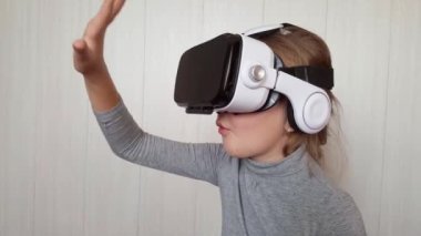 VR gözlüğü kullanan genç bir kız. Mutlu şirin kız, modern 3D VR gözlükleri kullanarak bir şeye dokunuyor. 4K 'da çekilmiş.