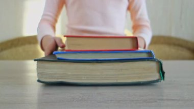 Genç kız masanın üzerine bir yığın kitap koyuyor. Bir genç kitap okur. Evde eğitim.