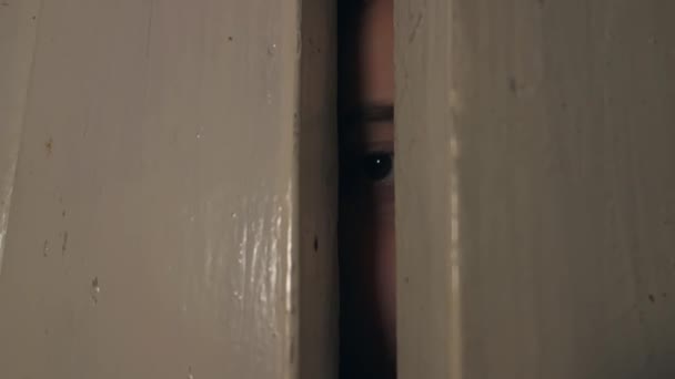 Une adolescente regarde par la porte pour vérifier ce qui se passe dehors. — Video