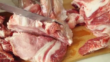 Eldivenli bir adam eti katman katman keser. Sulu, yağlı bir et parçası tahta bir tahtanın üzerinde bıçakla kesilir..