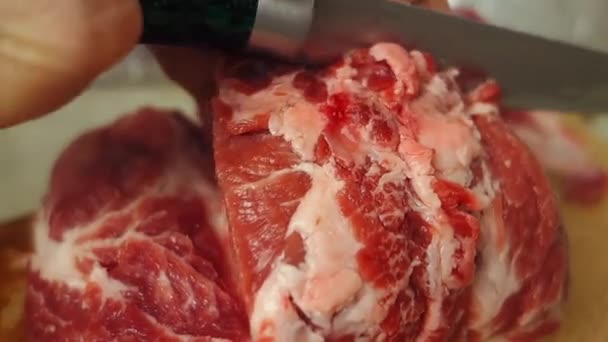 Τα γυναικεία χέρια κόβουν το κρέας σε κομμάτια από κοντά. Κομμάτι κρέας από κοντά σε μια ξύλινη σανίδα. Προετοιμασία των τροφίμων. — Αρχείο Βίντεο
