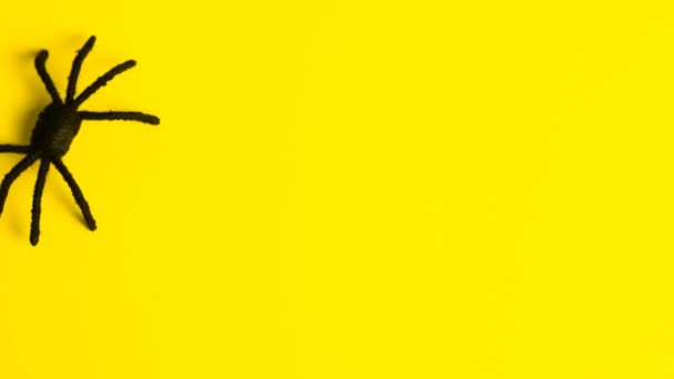 Una gran araña negra corre sobre un fondo amarillo y deja la inscripción Feliz Halloween. Detener vídeo en movimiento en 4k. — Vídeos de Stock