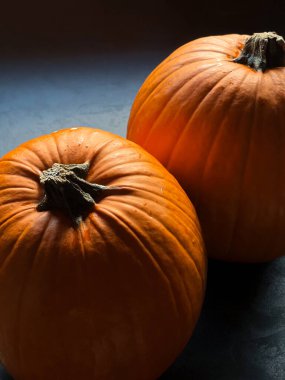 Close up of two ripe orange pumpkins on grey table, retro autumn harvest background