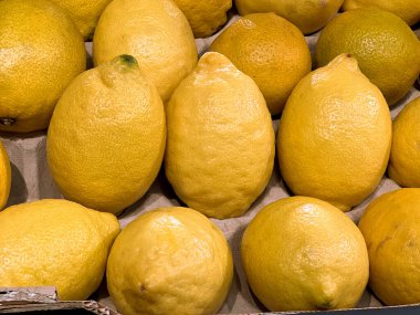 Close up of fresh ripe lemons on supermarket stall shelf. Organic bio citrus fruits sale