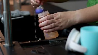 Süt için plastik bebek şişesini fırçayla temizleyen bir kadının yakın çekimi. Mutfak lavabosu. Yüksek kaliteli FullHD görüntüler