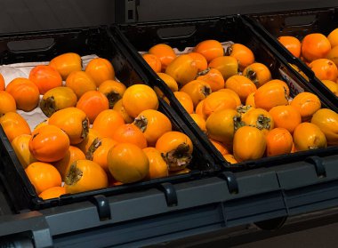 Close up of delicious fresh ripe persimmon fruits on a shelf at supermarket