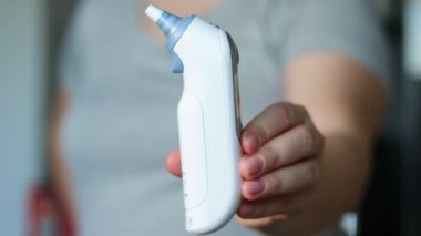 Modern dijital ateş termometresi tutan bir kadın, vücut ısısını kontrol ediyor. Yüksek kaliteli FullHD görüntüler