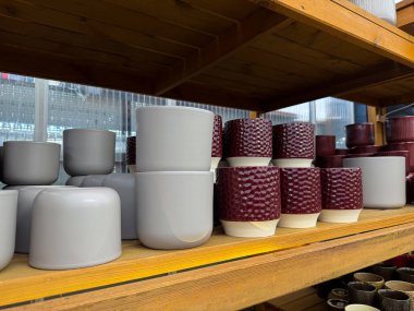 Bir bahçe dükkanının ahşap rafında farklı boş seramik saksıları var.