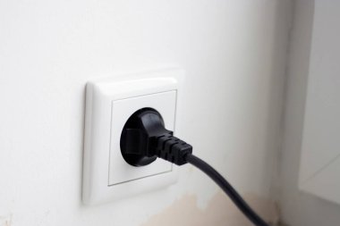 Sokete takılı siyah kabloyu kapat, beyaz duvar