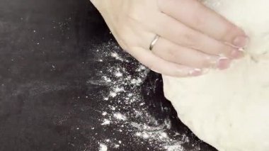 Kadın ellerini masaya yoğurup hamur hazırlarken kapatın ve dinlenmek için yuvarlak top yapın. Yüksek kaliteli FullHD görüntüler