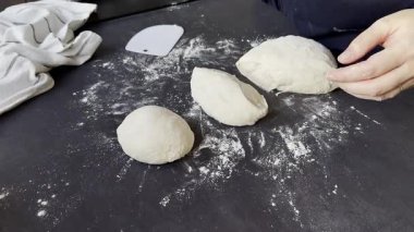 Kadın elleri, un grisi mutfak masasında taze hamur topları kesip şekillendiriyor. Yüksek kaliteli FullHD görüntüler
