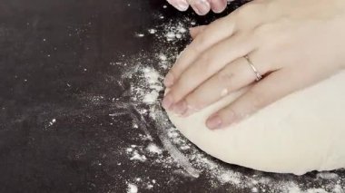 Kadın ellerini masaya yoğurup hamur hazırlarken kapatın ve dinlenmek için yuvarlak top yapın. Yüksek kaliteli FullHD görüntüler