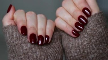 Koyu kırmızı tırnaklı kadın elleri, mükemmel kış ve sonbahar manikürü. Yüksek kaliteli FullHD görüntüler