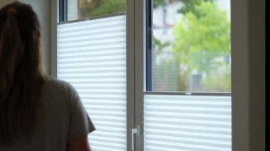 Beyaz jaluzi açan beyaz bir kadının yakın çekim penceresinde plisses, günışığının modern plisses gölgeleri. Yüksek kaliteli FullHD görüntüler