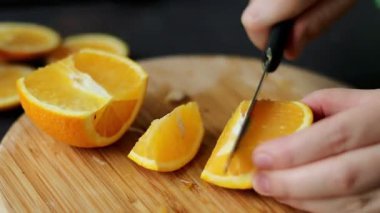 Kadın elinin ahşap kesme tahtasıyla taze bir portakal meyvesini keserken yakın plan. Yüksek kaliteli FullHD görüntüler