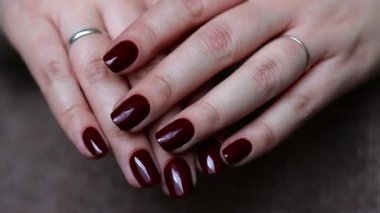 Koyu kırmızı tırnaklı kadın elleri, mükemmel kış ve sonbahar manikürü. Yüksek kaliteli FullHD görüntüler