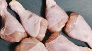 Çiğ tavuk budu, mutfak masasındaki yeşil plastik kesme tahtasının üzerinde, et pişirmek için hazırlanıyor.