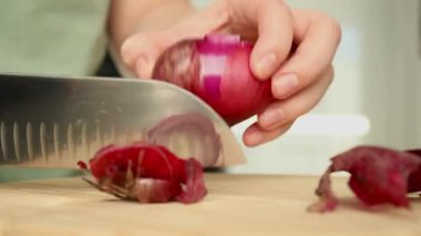 Bir dişinin tahta kesme tahtasındaki kırmızı soğanı bıçakla keserken görüntüsü. Yemek hazırlamak için. Yüksek kaliteli FullHD görüntüler