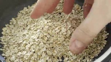 El, parlak bir mutfak ortamında yulafların dokusunu ve kalitesini ön plana çıkaran yuvarlanmış yulafların yüzeyini keşfeder.