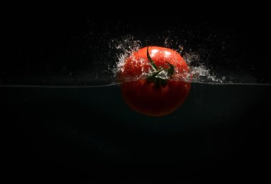 Siyah bir arka plan üzerine sıçramasına domates