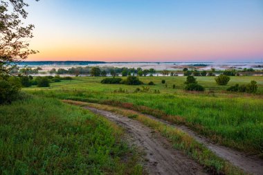 Sabah sisi olan görkemli nehir vadisi. Ön planda köy yolu var. Ukrayna 'nın kırsal ve doğası, Harkiv Oblastı
