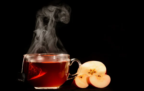 Chá com maçã ainda vida em um fundo preto com vapor visível — Fotografia de Stock
