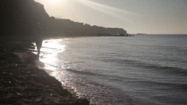 Bir adam deniz kıyısında yürüyor.