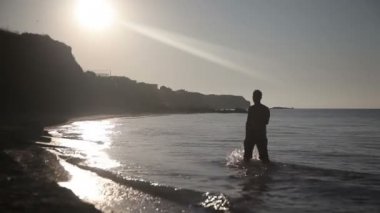 Bir adam deniz kıyısında yürüyor.