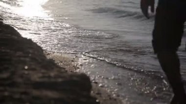 Bir adam deniz kıyısında yürüyor.