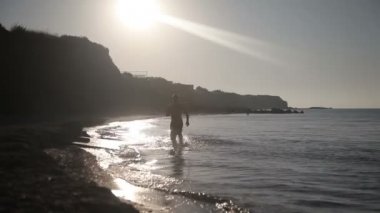 Kumsalda güneş doğarken koşan adam.